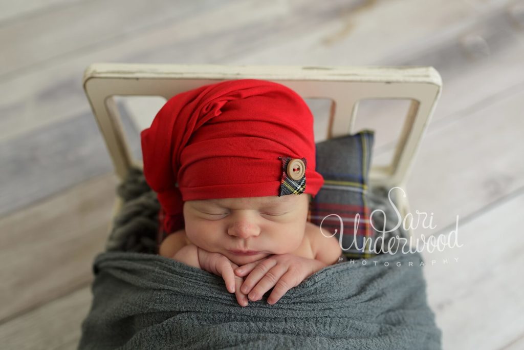 baby snuggled in bed with christmas hat
