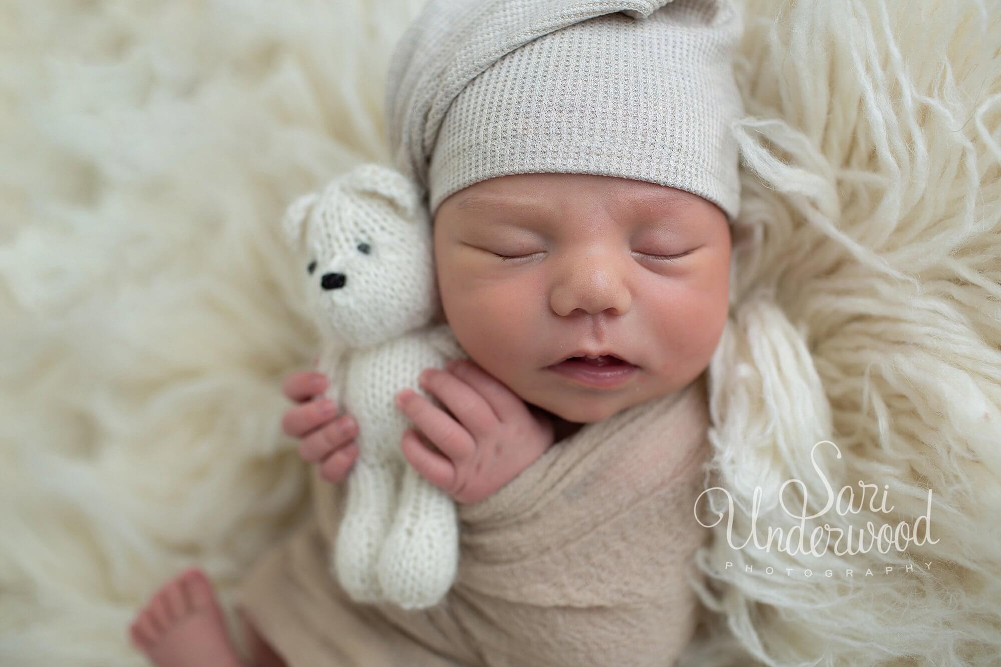 newborn baby boy cuddling a bear stuffie