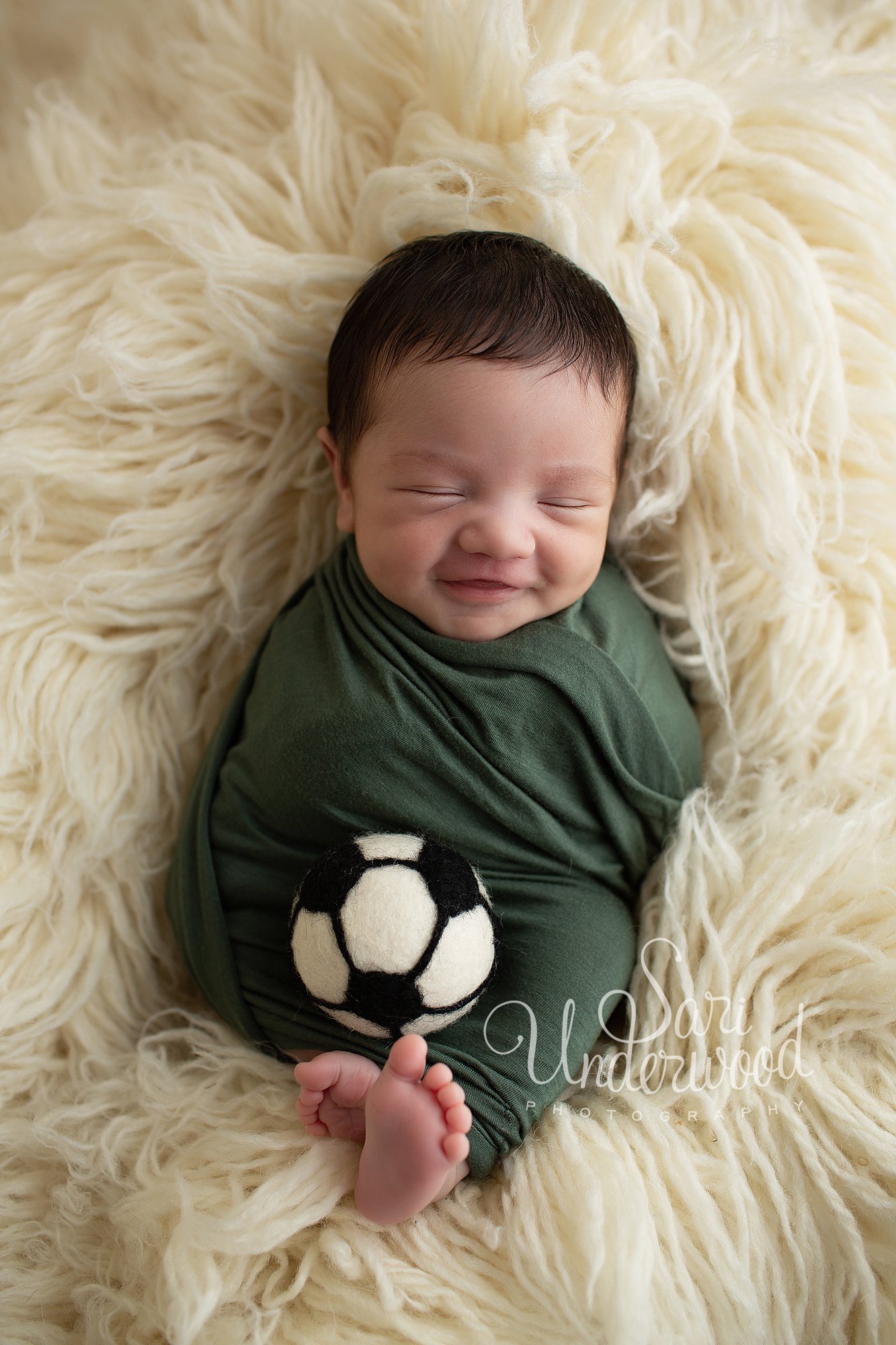 newborn baby boy smiling with a soccer ball