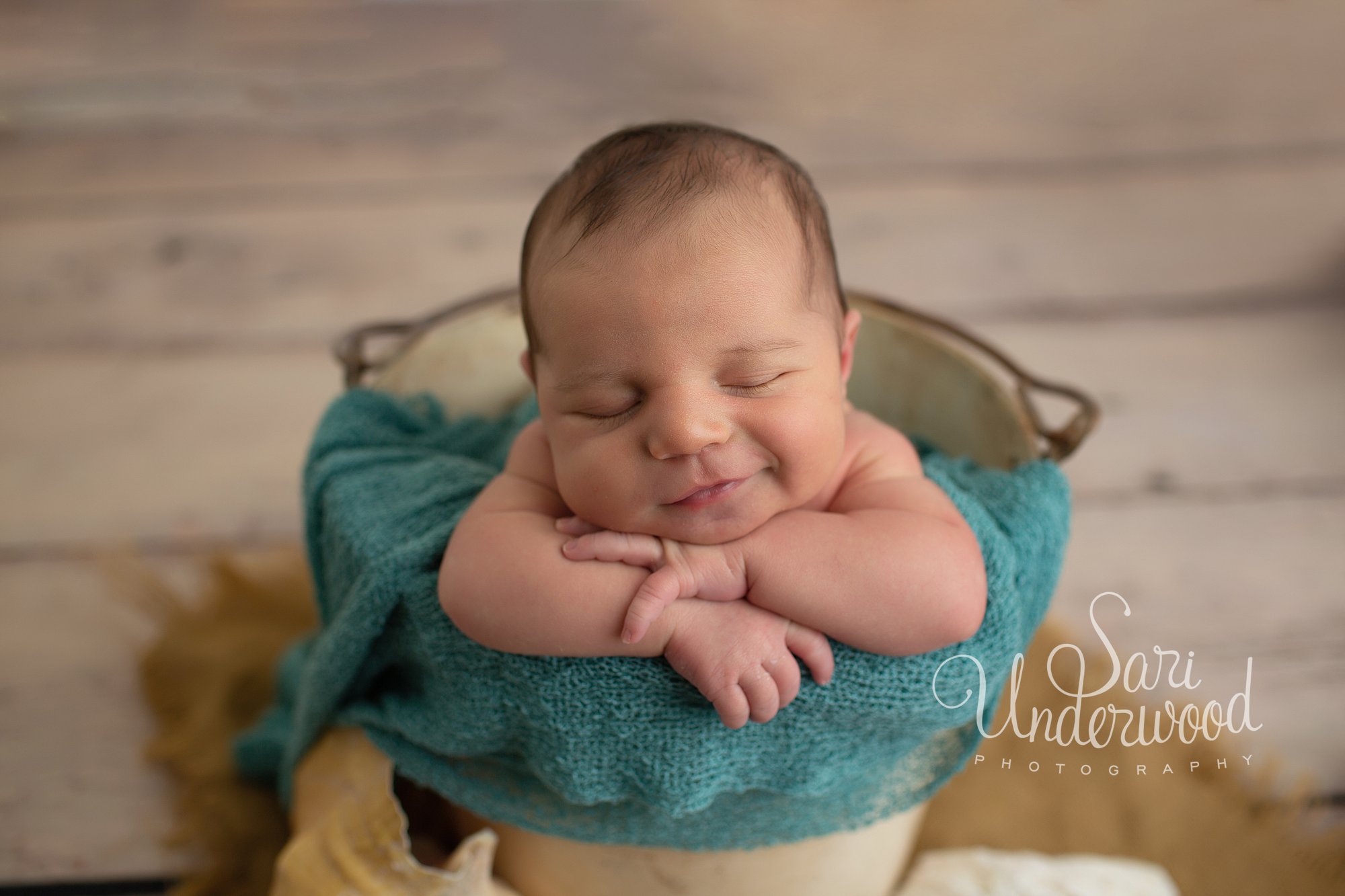 newborn baby boy in a bucket smiling
